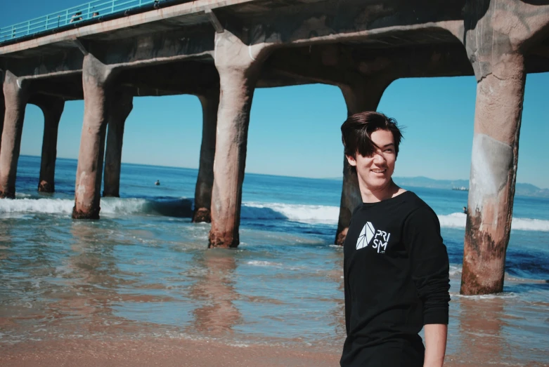 a person standing in the surf under a bridge