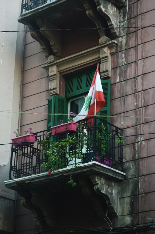 an open green door and green balcony and two flags