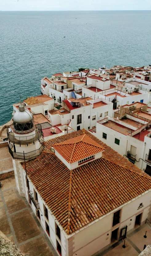 aerial po looking down on colorful red tiled buildings and the ocean in the background