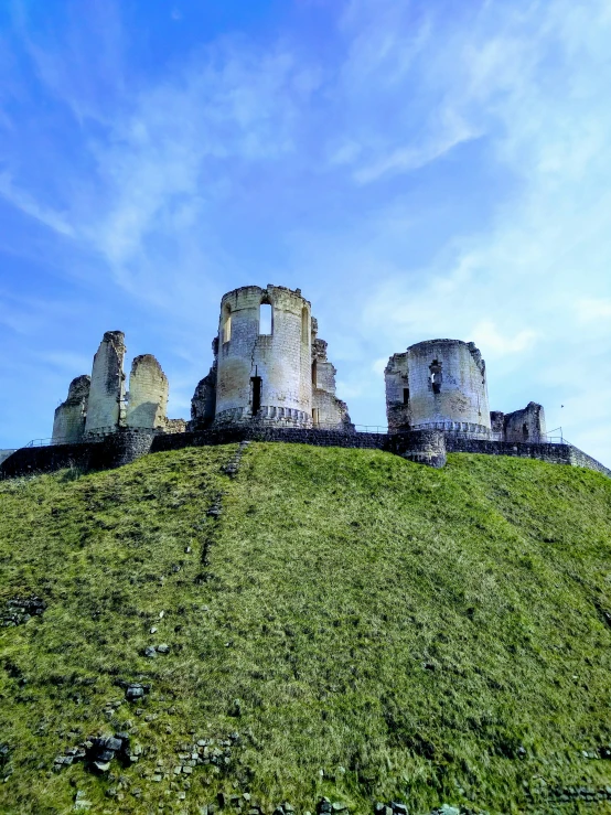 a stone castle sitting on top of a green hill