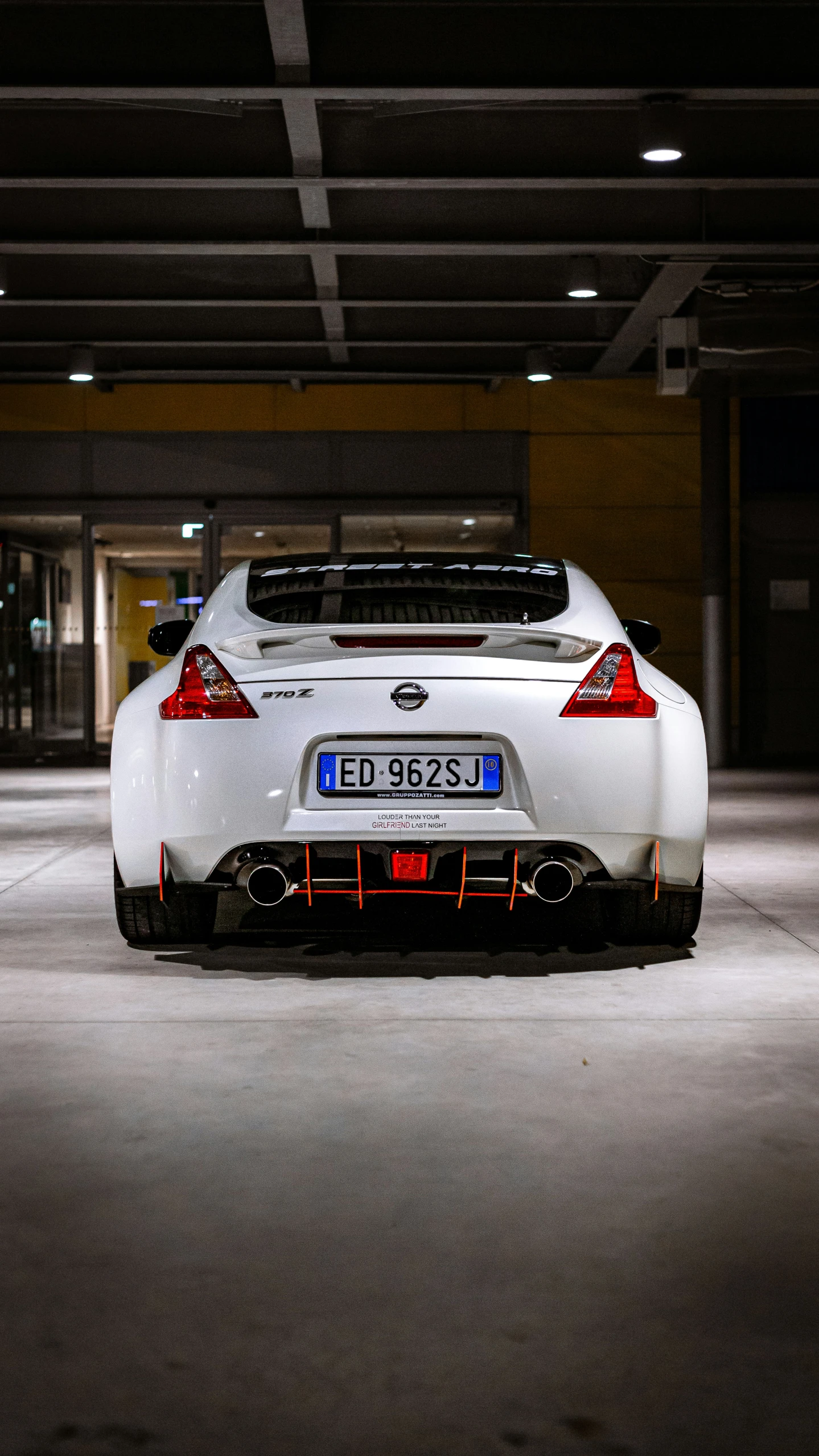 the rear end of a white car in a parking garage