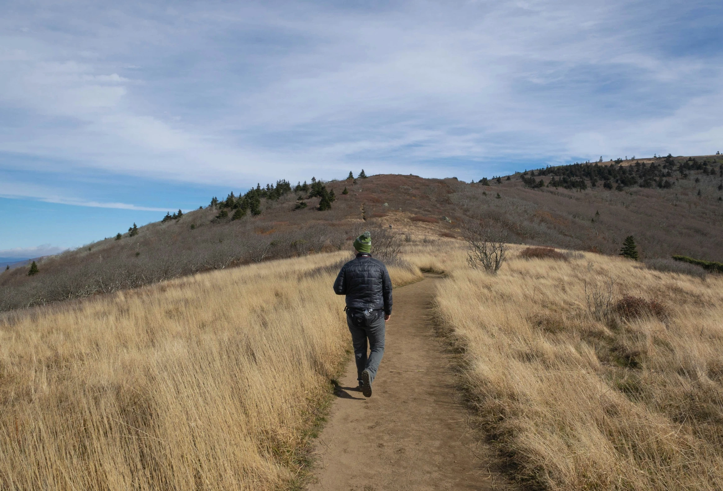 the man is running down the trail in the field