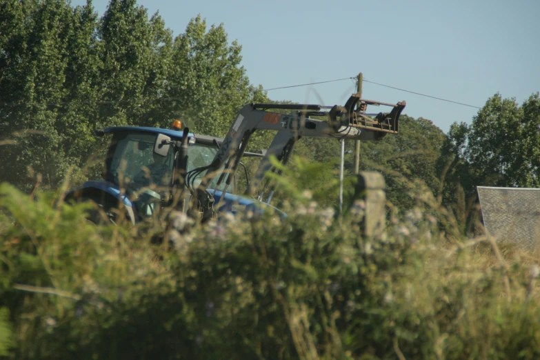 a couple of blue tractors in front of trees