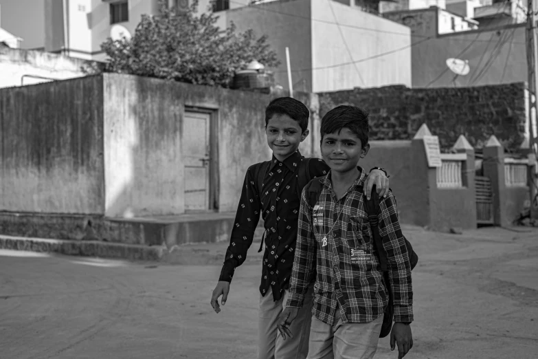 two boys are walking down the street on a sidewalk