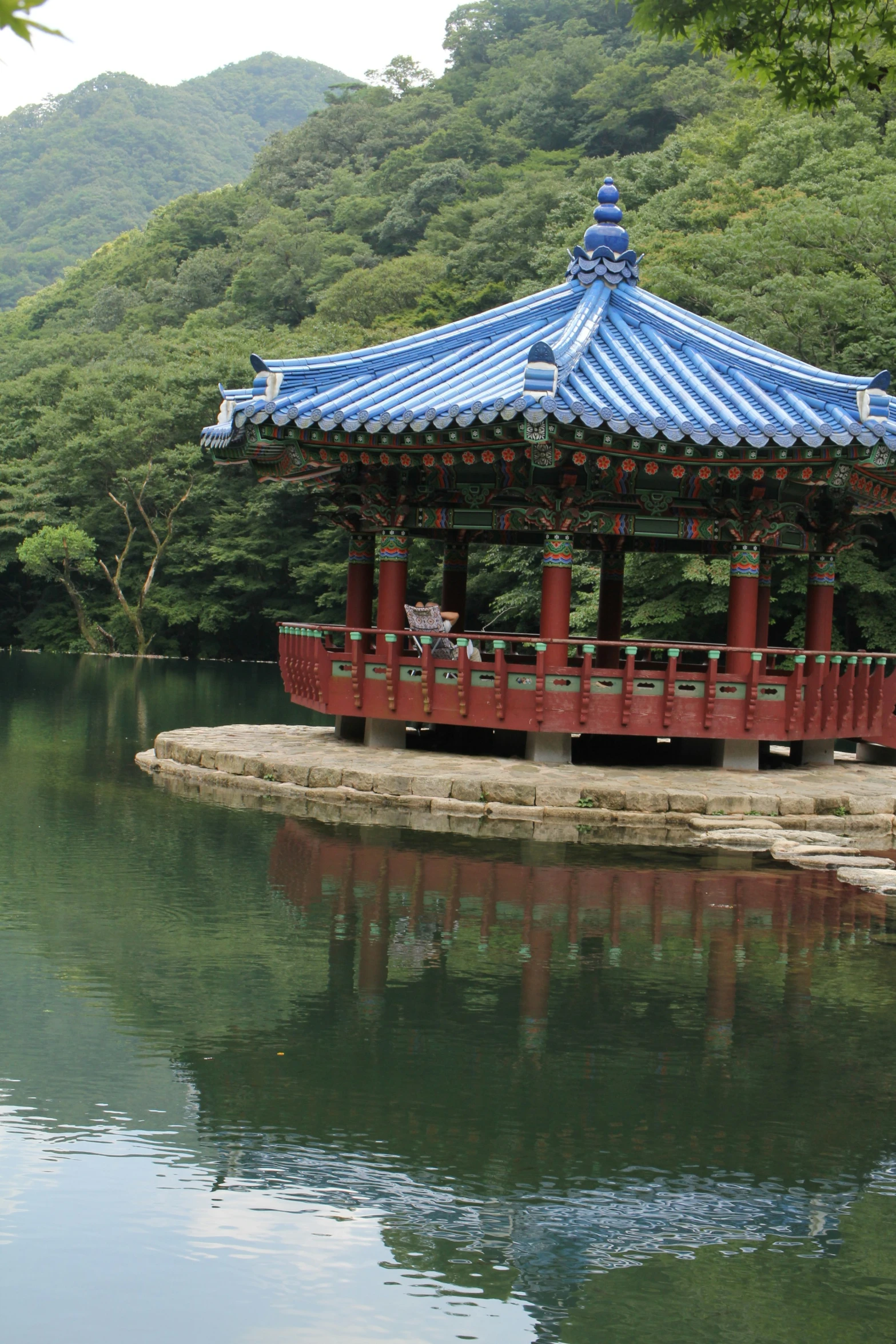 an oriental structure in a park surrounded by water