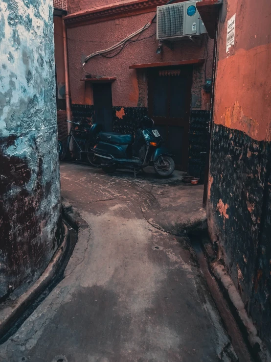 a narrow street with a small motorcycle parked next to it