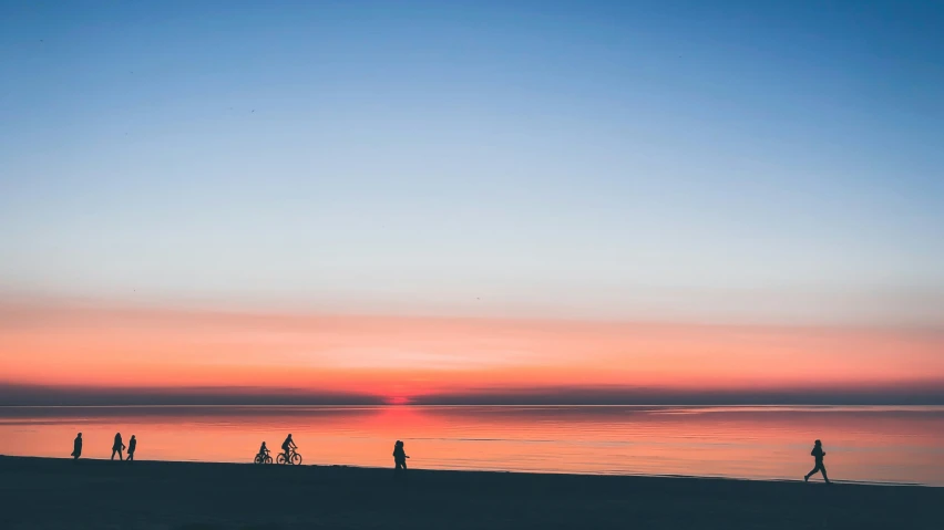 a group of people on the beach watching the sun set