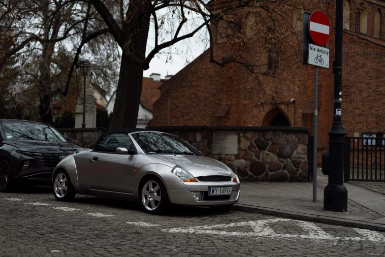 a gray and black sports car in front of an old brick building