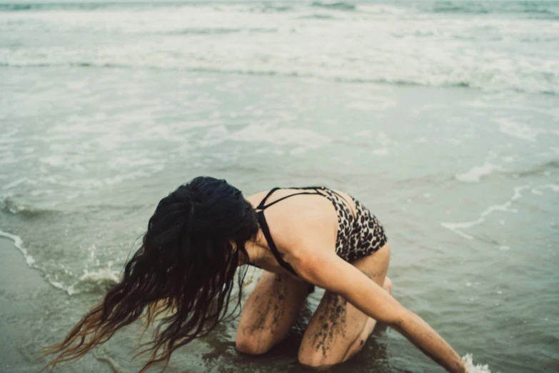 a person crouching in the water on the beach