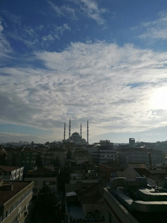 a cityscape shows the silhouettes of a church and other buildings under a partly cloudy blue sky