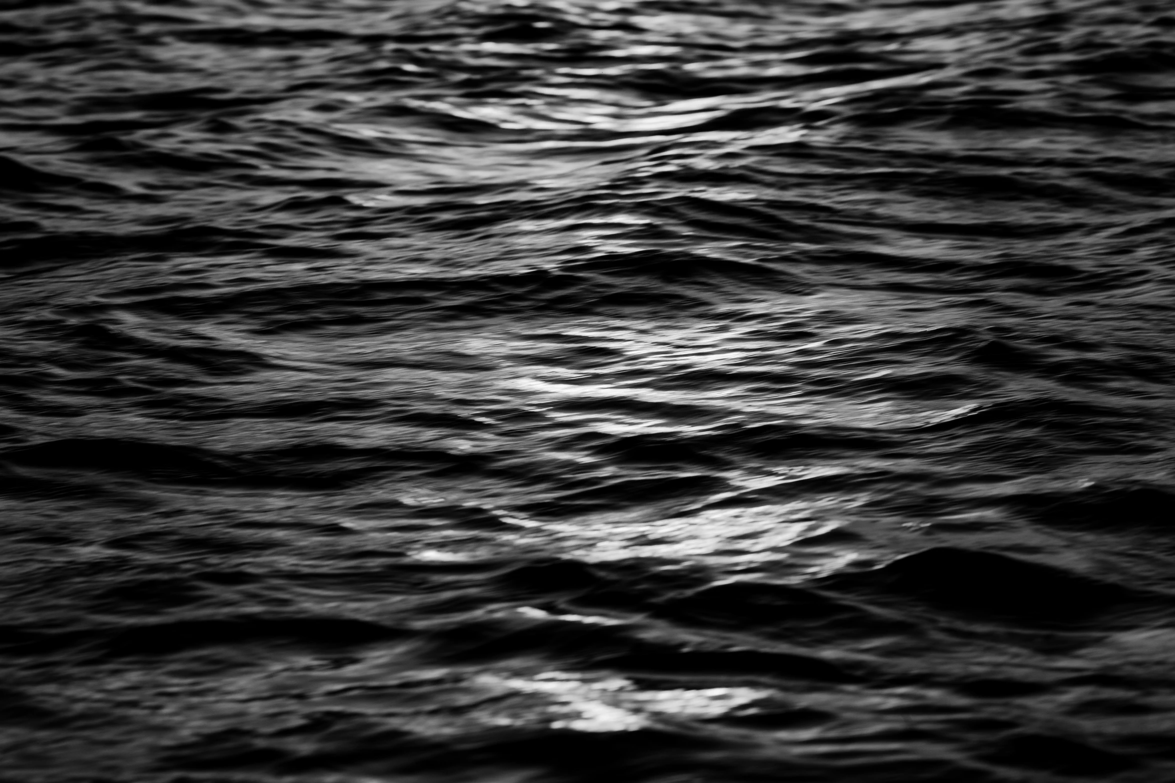 dark ocean water at night with dim light shining through the clouds