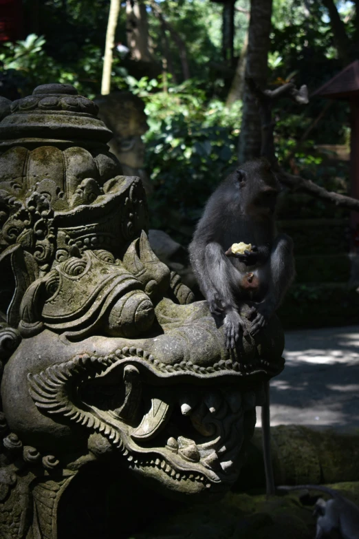 a monkey sitting on top of a stone statue eating