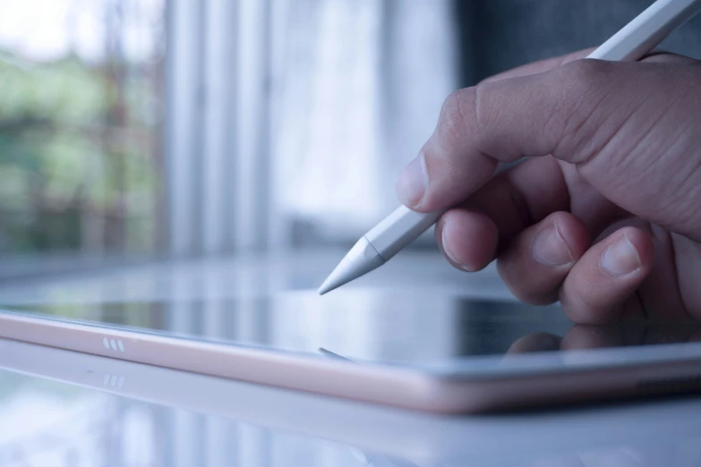 the person is writing on the tablet with a pencil