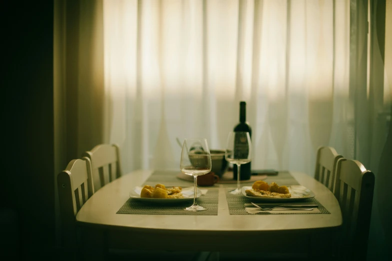 a table has two plates with food on it and bottles of wine