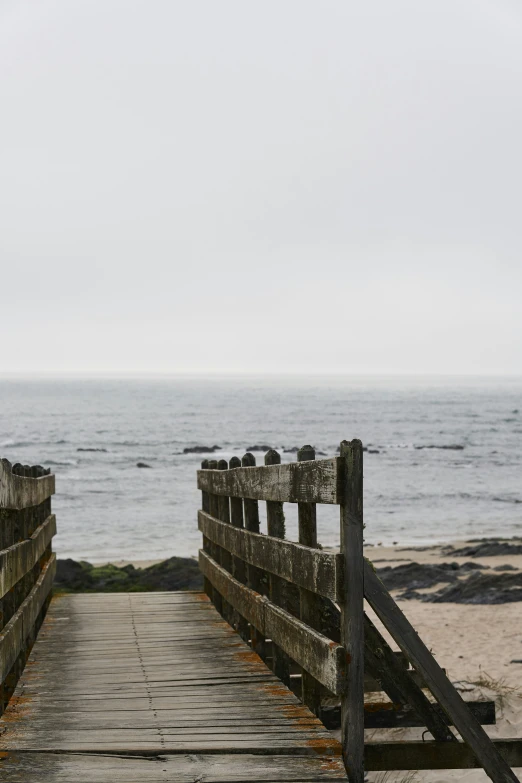 a bridge that leads to the beach with a view of water and sand