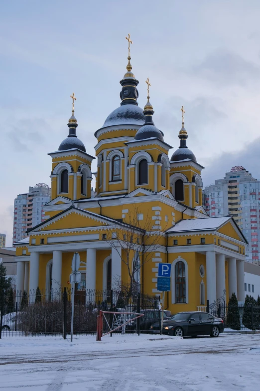 yellow church with three clocks on the tower and many white pillars