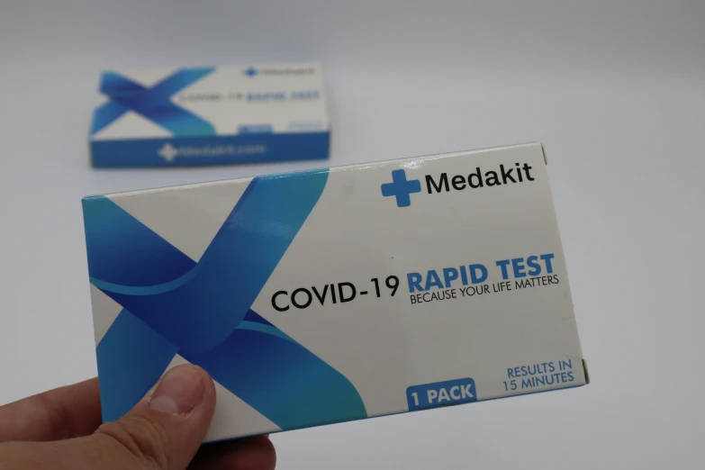 a person holds up a card that reads covidd - 19 rapid test