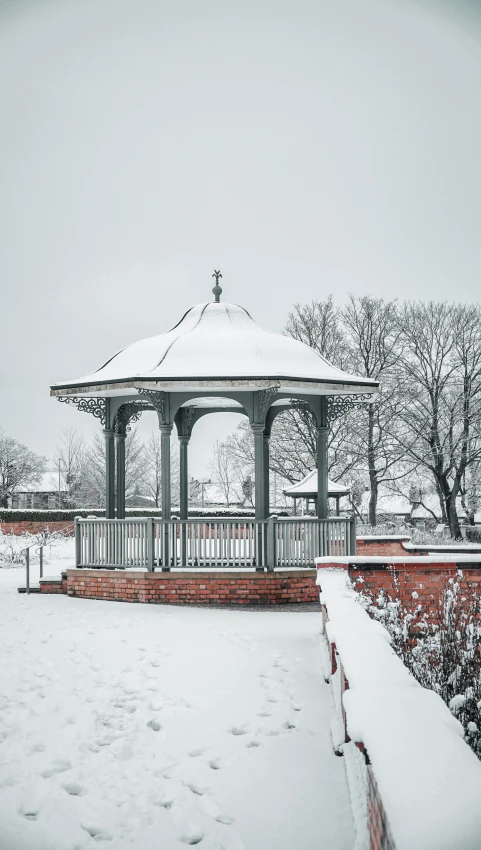 a gazebo and bushes are covered with snow