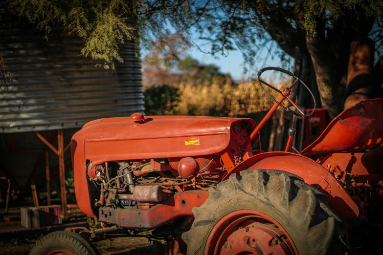 a rusted red tractor parked on the side of a road