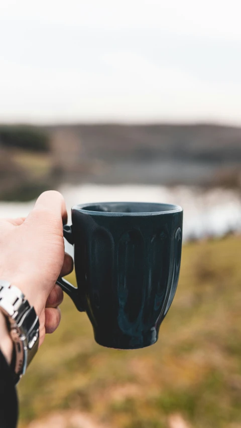 a person holding a black coffee cup outside