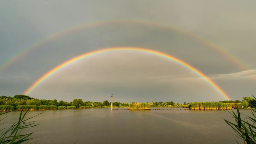 two rainbows are shining over the water of a lake