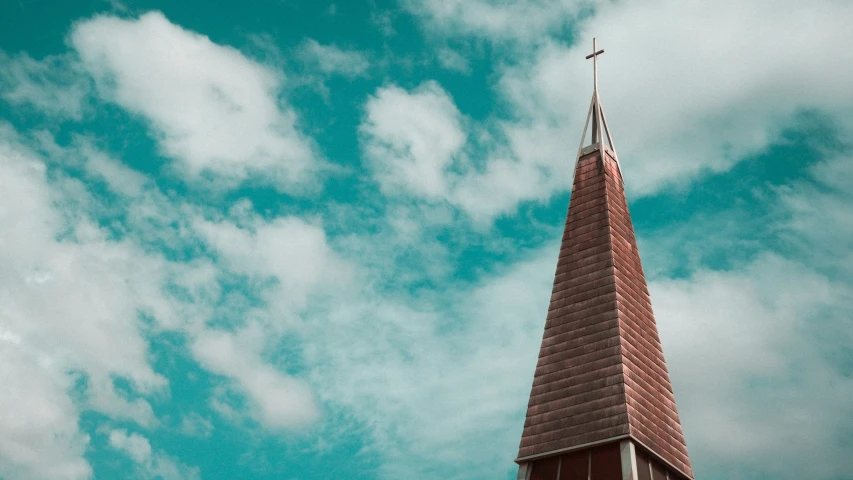 a small red steeple and cross against a partly cloudy sky