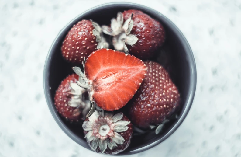 this is a black bowl filled with strawberries