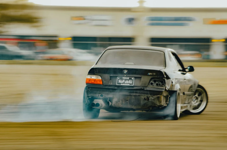 a man is driving a car around a lot of smoke