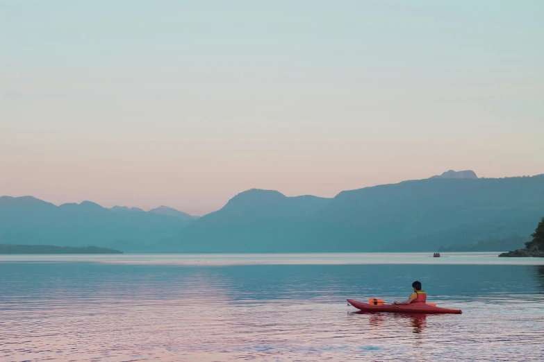 a person in a red kayak paddling on a calm lake