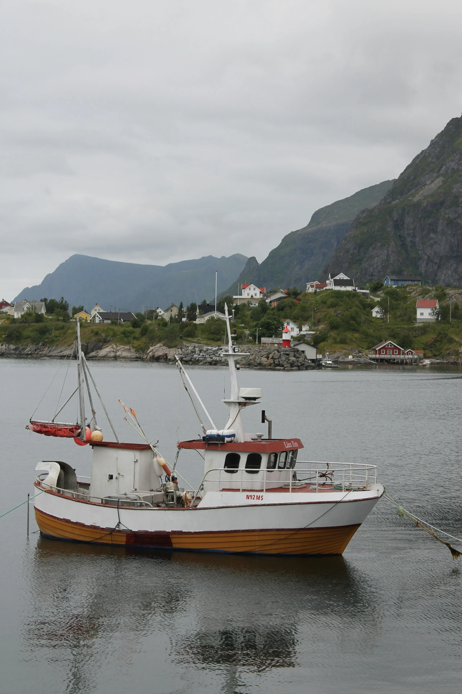 a white boat with a red bow is docked in the water