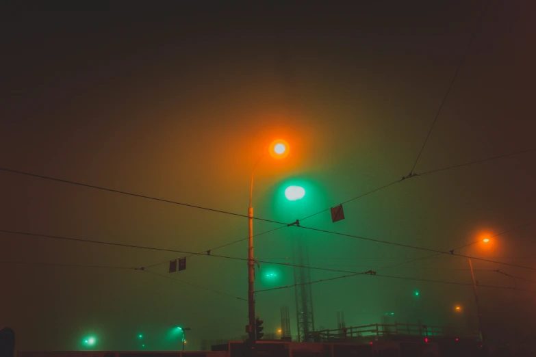 two green lights over the street from the traffic lights