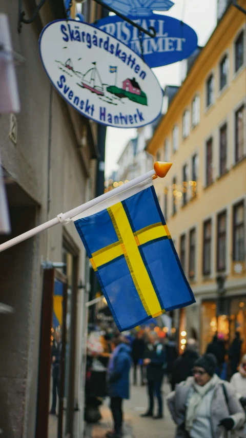 blue and yellow flags with a swedish flag hanging off the side of a building