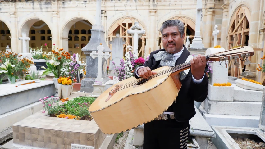 a man playing an instrument while standing next to flowers
