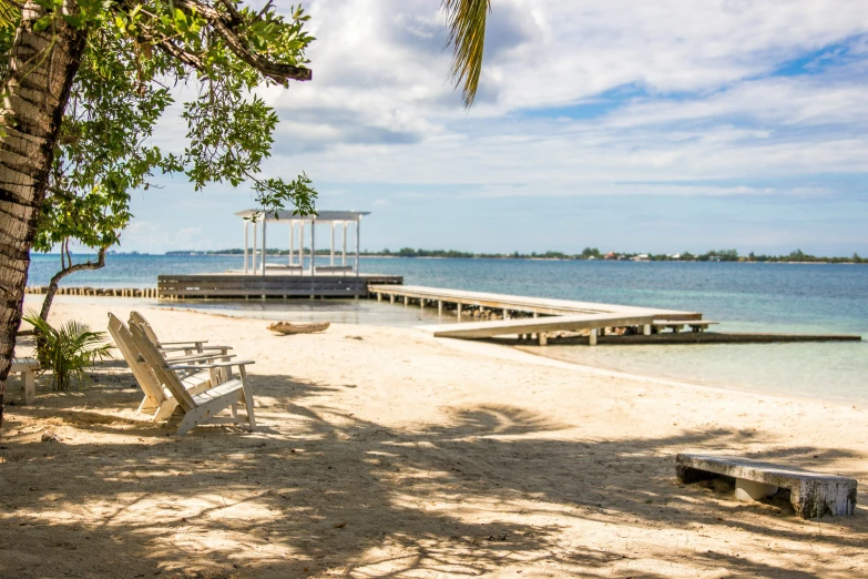 a dock and benches sit in the sand near the water