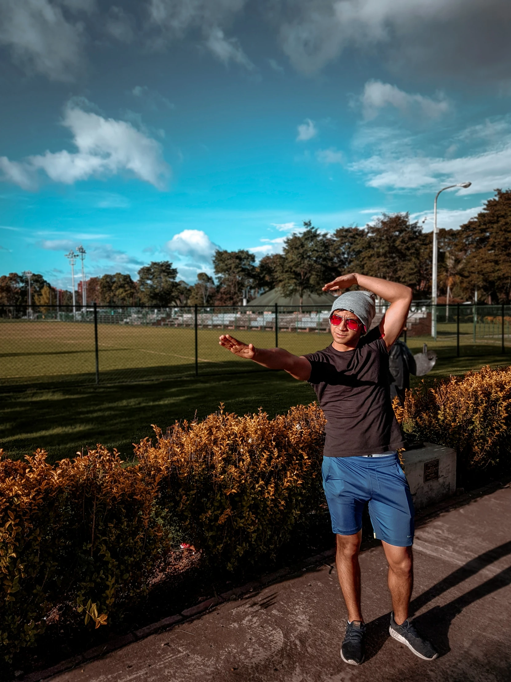 man wearing sunglasses standing in the sun on concrete