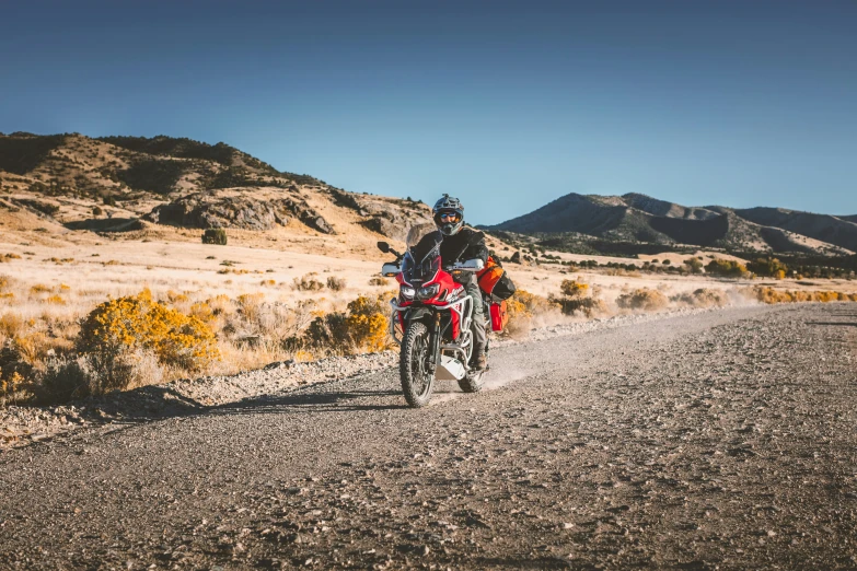 the man is riding the motorcycle on the dirt road