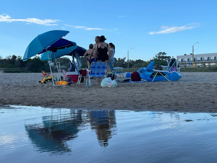 people with beach chairs and umbrellas are looking at the water