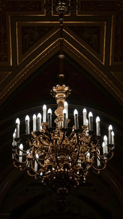 a chandelier in a church that has candles lit
