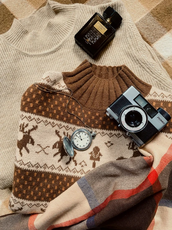 there is an old po of a sweater, watch and camera on the floor