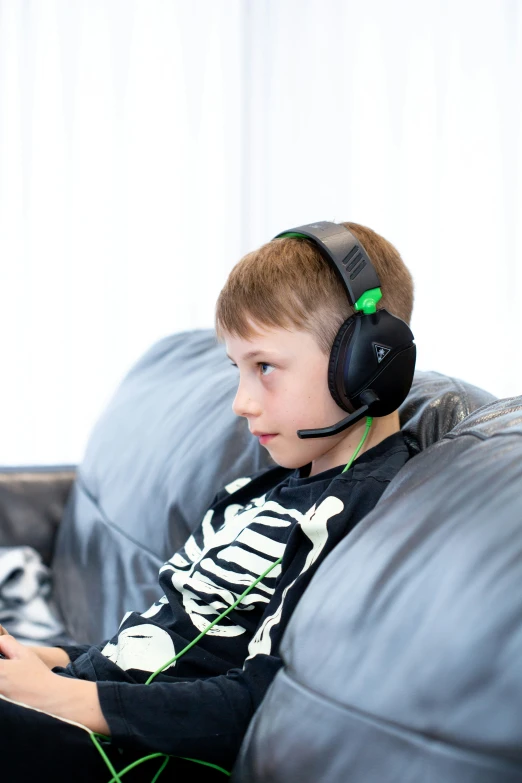 a little boy sitting on a couch wearing headphones