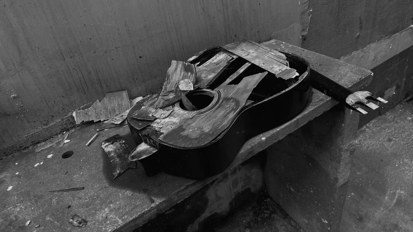 a broken guitar and its case on a wall