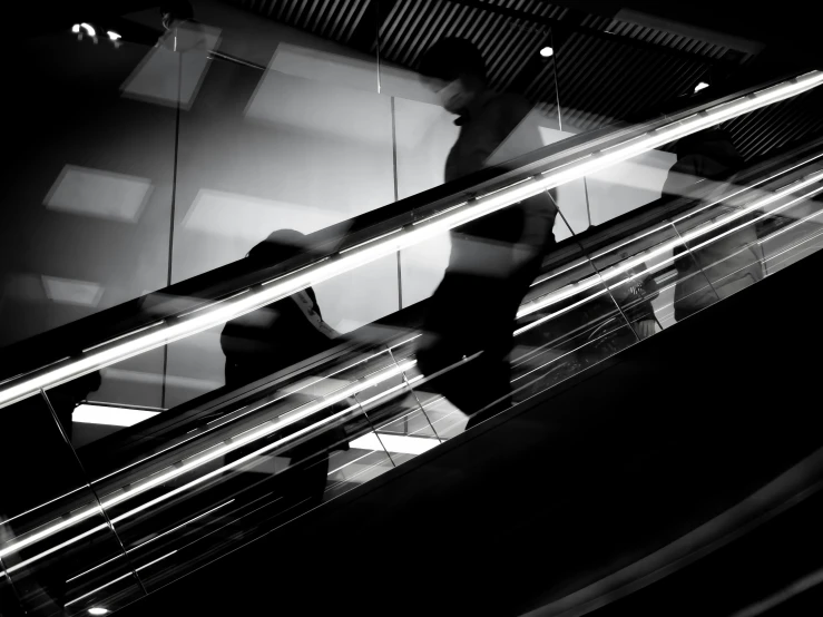 man in jacket at an escalator in black and white