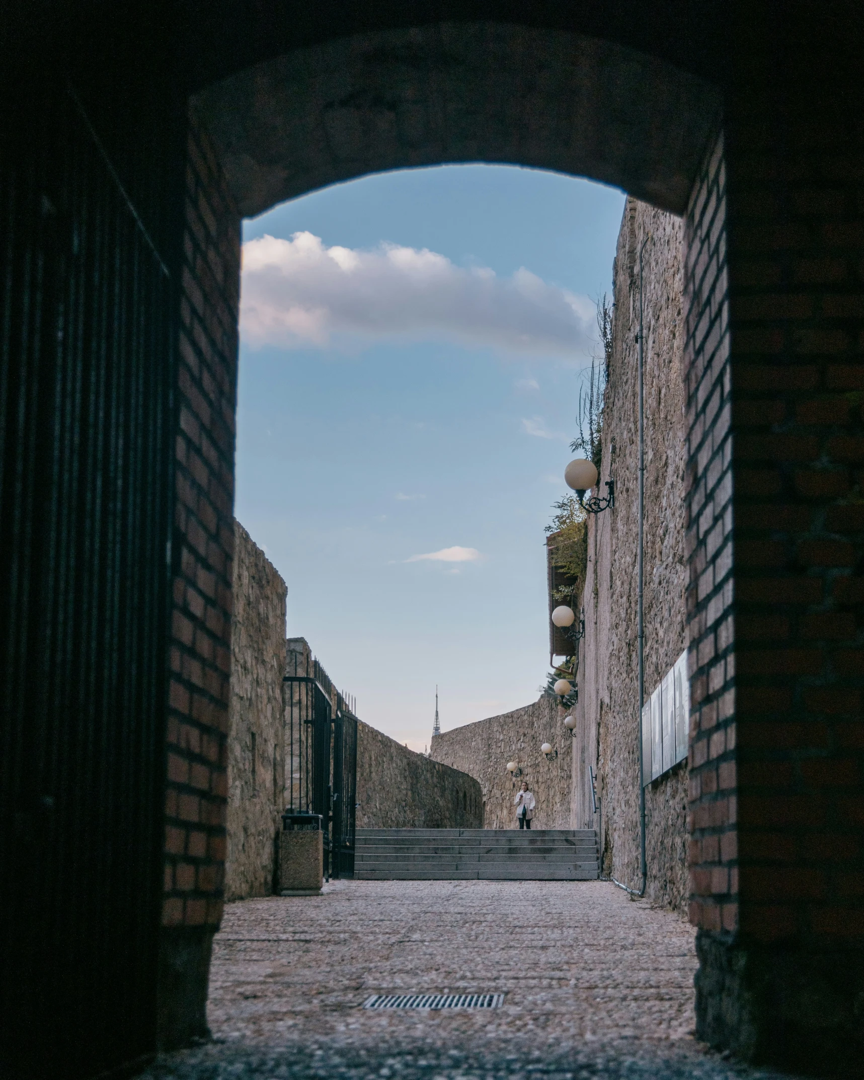 a person walking down a street next to a brick wall