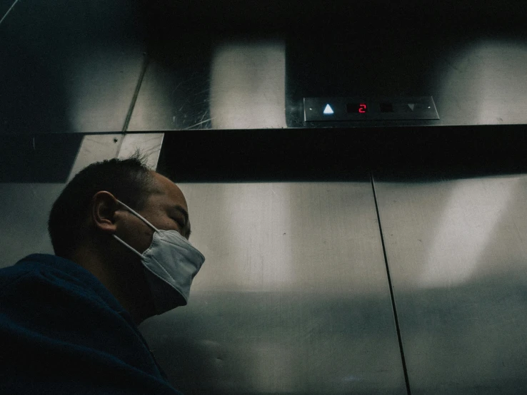 man in protective face mask near metallic elevator