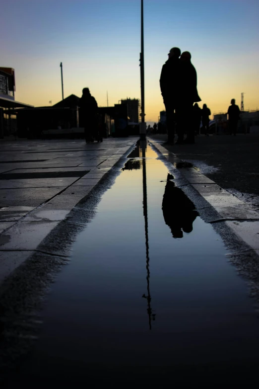 people standing on the side walk reflected in a dle