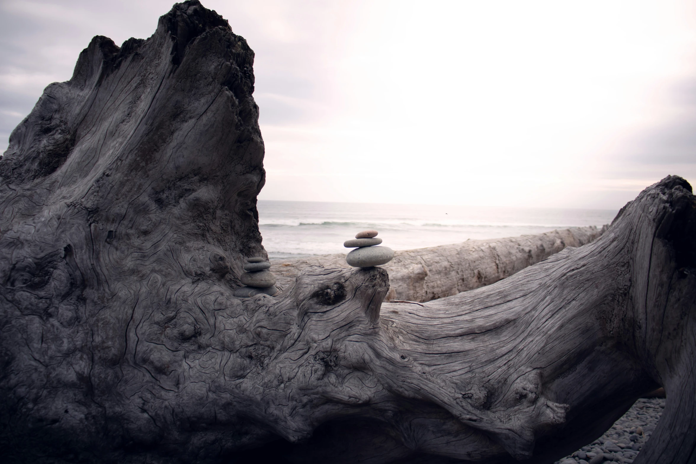 two stacked rocks are on a beach with waves