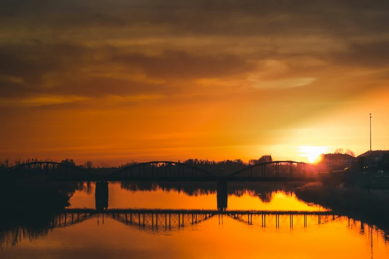 a lake at sunset with sun in the distance