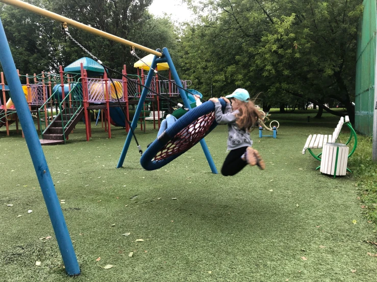 a little girl playing on the swings at a playground