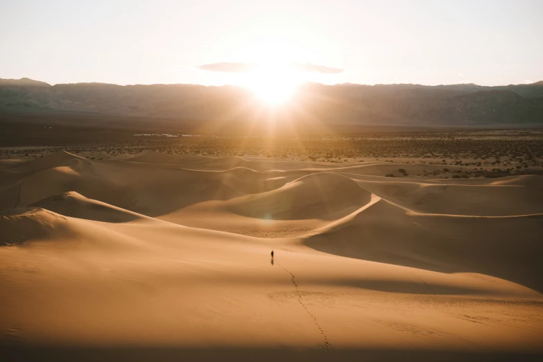 the sun peeking behind a cloud over a sandy desert landscape