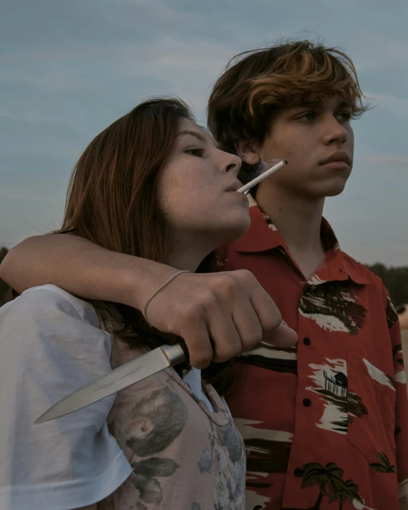 a young man standing next to a woman with a cigarette